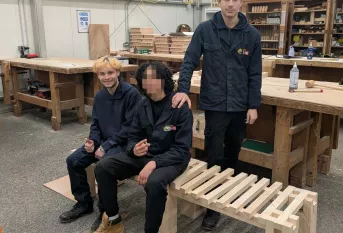 3 élèves en cap menuiserie assis sur le banc qu'ils ont fabriqué