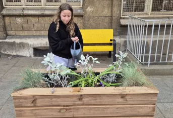 Une élève arrose des fleurs dans un pot
