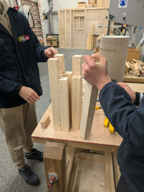 2 élèves tiennent des tasseaux de bois pour la préparation du projet