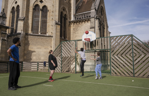 Deux jeunes accompagnés de leurs éducateurs en train de jouer au basket