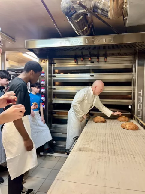 Le boulanger montre aux jeunes les pains sortis du four