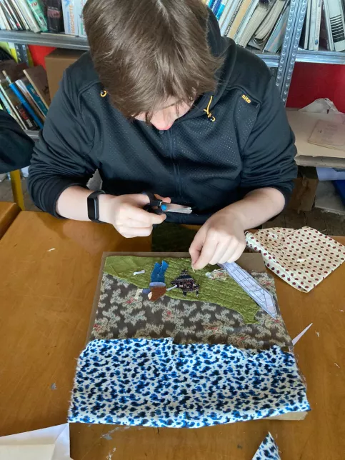 Elève en train de travailler sur sa création textile (découpage collage)