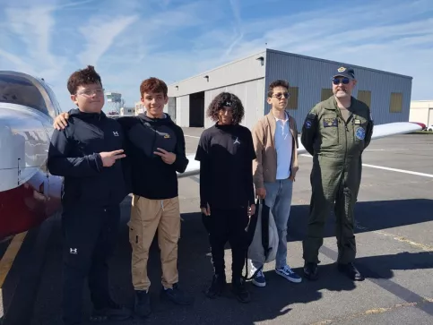 Jeunes avec un professionnel de l'aéronautique devant un avion
