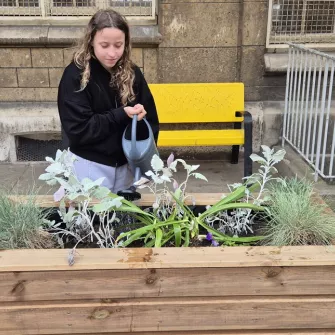 Une élève arrose des fleurs dans un pot