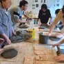 Elèves autour d'une table qui aplatissent de l'argile avec un rouleau